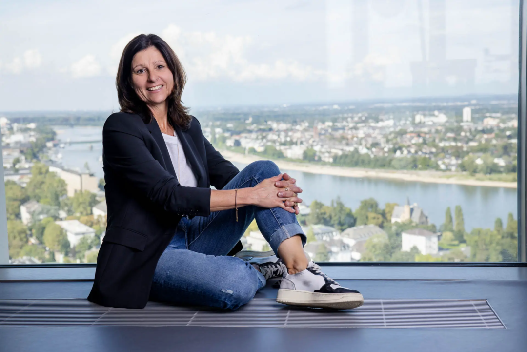 Immobilienmaklerin sitzt am Boden in der 27. Etage am Kanzlerplatz in Bonn und schaut freundlich in die Kamera