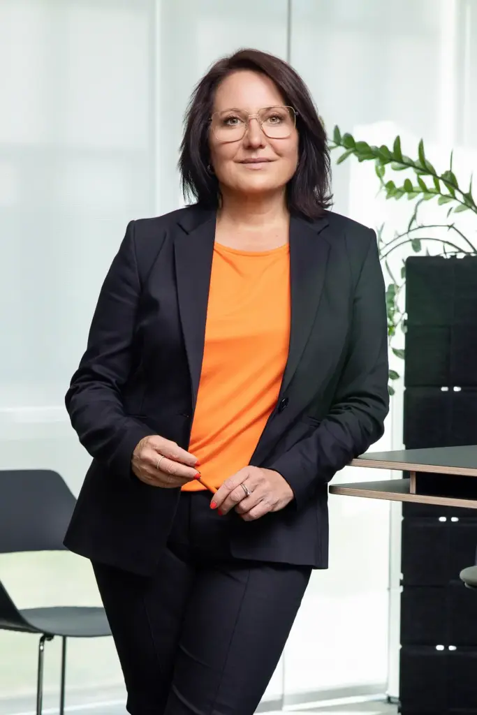 Unternehmerin im orangefarbenen Shirt auf dem Sofa – entspanntes Business-Portrait für Social Media