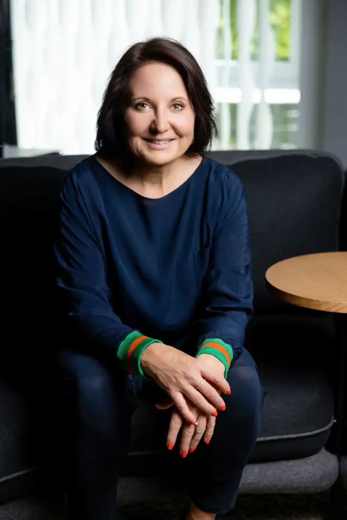Unternehmerin in dunkelblauem Outfit sitzend auf dem Sofa – entspanntes Personal Branding Portrait