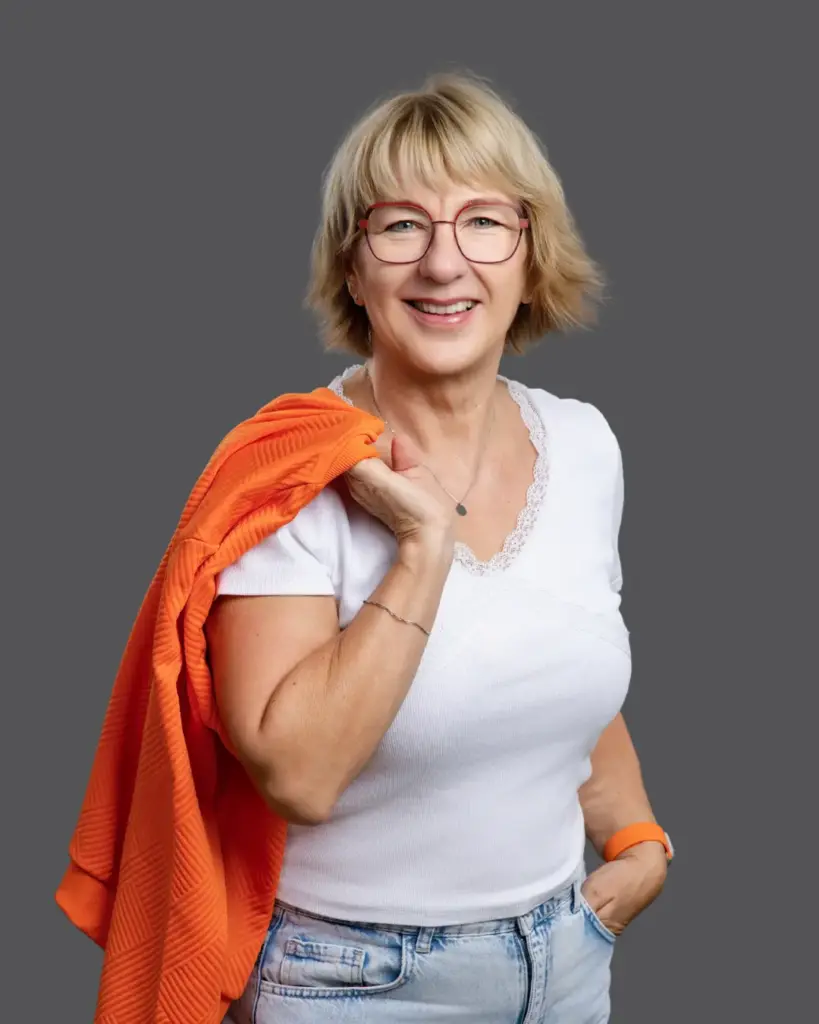 Fragen und Antworten von Karina Schuh Markenfotografin für Personal Branding und Unternehmen - hier mit orangefarbener Jacke über der Schulter