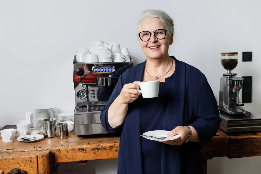 Dagmar Gösling trinkt lächelnd einen Kaffee an der Kaffeebar bei designfunktion Koblenz