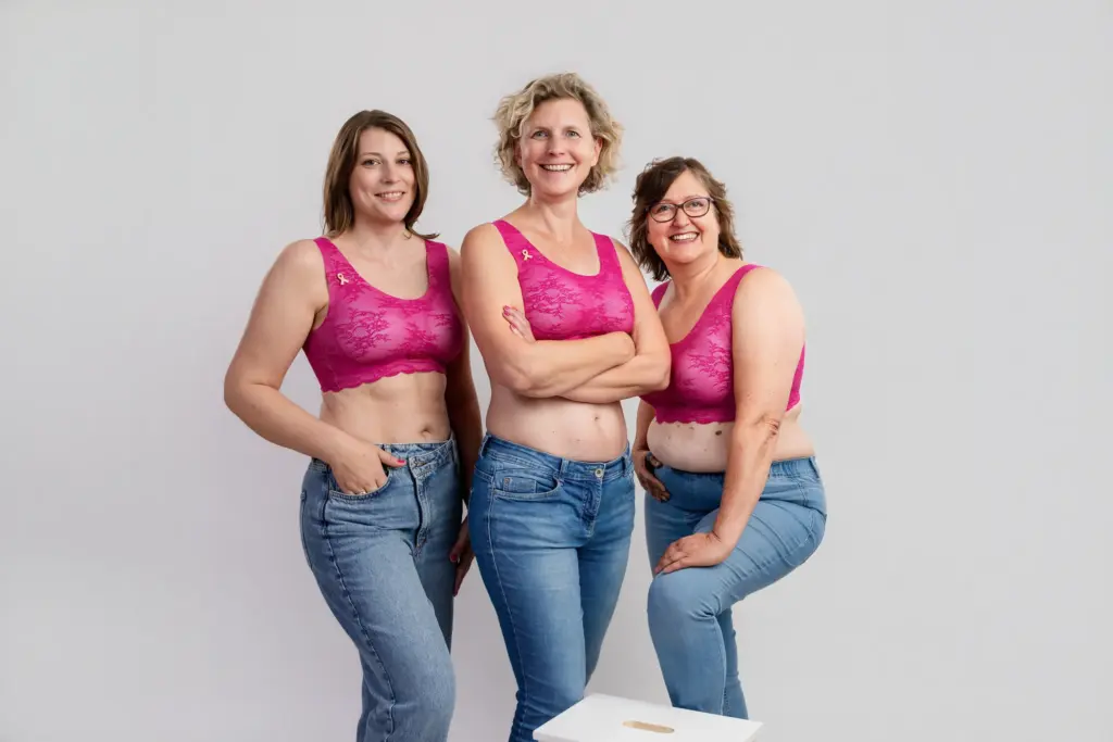 Drei Frauen in pinken BHs und Jeans stehen selbstbewusst nebeneinander, Pinktober-Kampagne Koblenz 2026