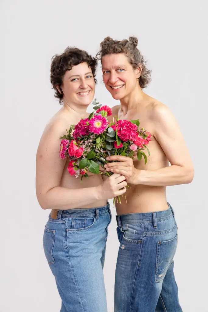 Zwei Frauen stehen eng beieinander und halten gemeinsam einen pinken Blumenstrauß, Pinktober Koblenz 2026