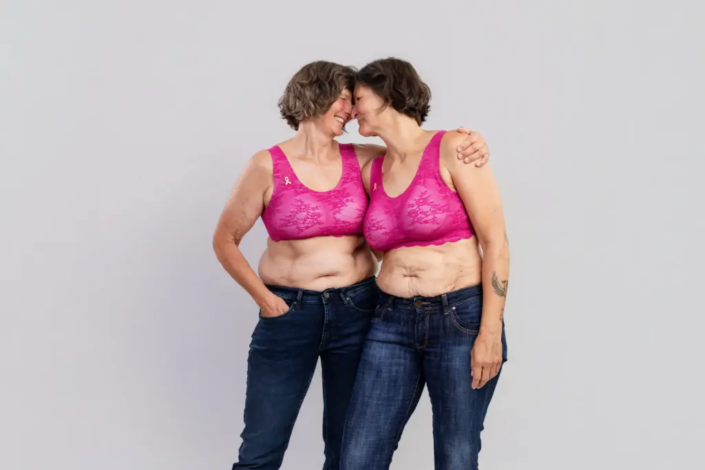 Zwei Frauen in pinken BHs lehnen vertraut die Köpfe aneinander, Pinktober Koblenz 2026