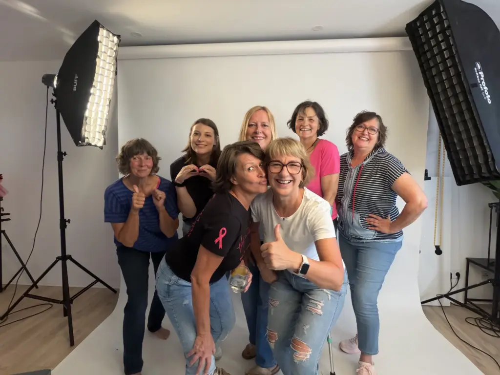 Sieben lachende Frauen der Pinktober-Kampagne Koblenz 2026 posieren fröhlich im Fotostudio von Karina Schuh zwischen den Studioleuchten