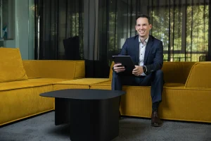 Steuerberater Tobias Junges sitzt mit Tablet auf einem gelben Sofa bei designfunktion, Businessfotos für die Website