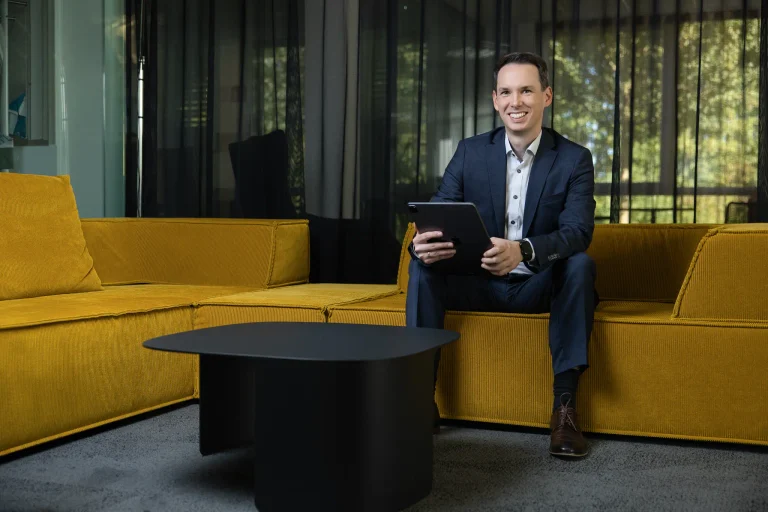 Steuerberater Tobias Junges sitzt mit Tablet auf einem gelben Sofa bei designfunktion, Businessfotos für die Website