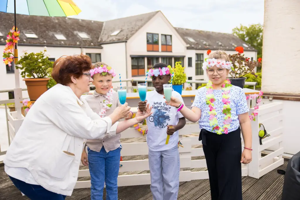 Erzieherin mit drei Kindern bei der Cocktailparty auf der Dachterrasse im St. Vinzenzhaus Einrichtung der Kinder- und Jugendhilfe